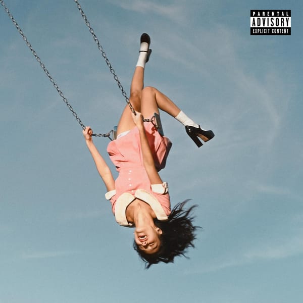 Cover art for Olivia Rodrigo's latest album, a photo of her swinging in a park swing against a blue sky. She wears a pink dress and is upside down from the viewer perspective